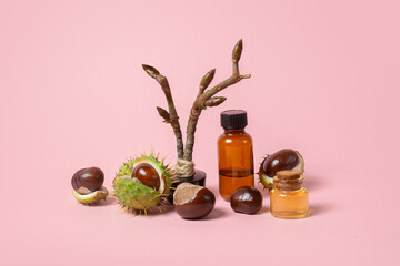 Autumn horse chestnut with peel, chestnut sprig with buds, bottles with oil and chestnut extract on a pink background - 657690972