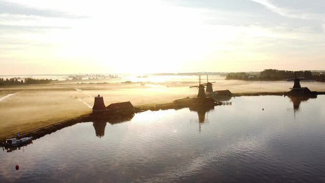 Ancient wooden windmills of Zaanse Schans during sunrise. The golden rays reveal the history of the Netherlands. 4k video
