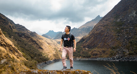 Hombre parado al lado de una laguna en las montañas (Laguna Metras, Linda Linda, Pachitea, Perú) - obrazy, fototapety, plakaty