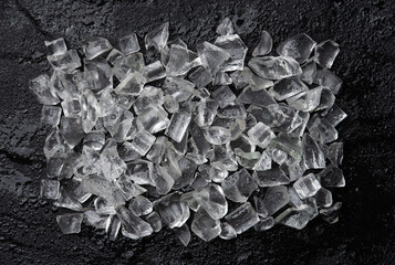 Pile of crushed ice cubes on black stone background, top view with copy space