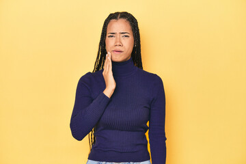 Young Indonesian woman on yellow studio backdrop having a strong teeth pain, molar ache.