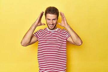 Young Caucasian man on a yellow studio background joyful laughing a lot. Happiness concept.