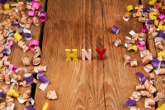 Happy New Year lettering, gift box with confetti on wooden background. Festive atmosphere. New year concept.