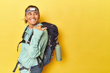 Mountain gear and frontal light on yellow points with thumb finger away, laughing and carefree.