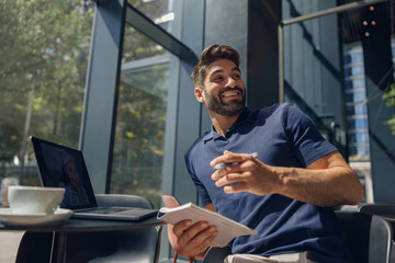 Smiling businessman have business meeting via video call sitting in cafe and looks away