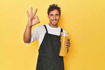 Young latino man cook with pasta jar on yellow cheerful and confident showing ok gesture.