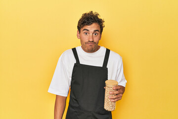 Chef with chickpeas jar on yellow shrugs shoulders and open eyes confused.