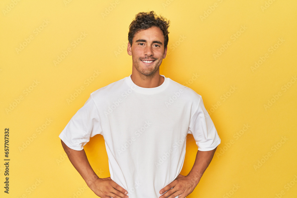 Wall mural young latino man posing on yellow background confident keeping hands on hips. - Wall murals