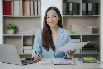 Happy Asian businesswoman working in modern office using laptop computer