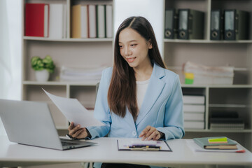 Happy Asian businesswoman working in modern office using laptop computer