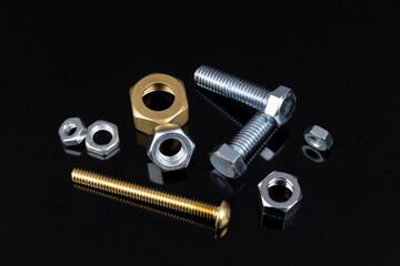 Silver bolts and gold nuts on a reflective, metallic background