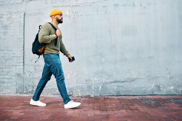 Walking, student and travel with man on wall, mockup and space in urban, campus or street in town. University, person and commute on path, road or journey to college in city with phone or backpack - obrazy, fototapety, plakaty