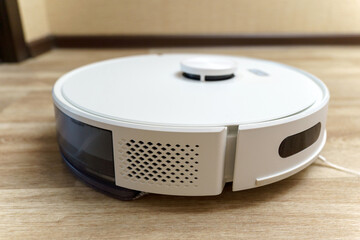 White robotic vacuum cleaner on linoleum floors smart cleaning technology. Selective focus