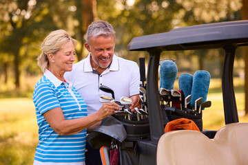 Fototapeta na wymiar Senior Couple Standing Next To Buggy On Golf Course Choosing Clubs Together