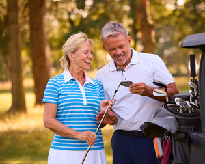 Senior Couple Standing Next To Buggy On Golf Course Choosing Clubs Together