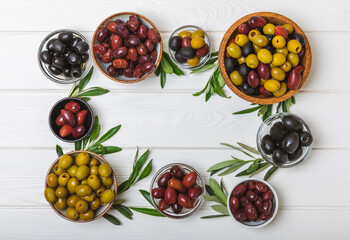 Green and black olives on a textured background. Different types of olives in bowls and olive oil with fresh olive leaves. Delicacy.Mediterranean Kitchen. Copy space.
