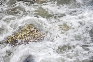 The waves break on the rocks. Rocky shore. The coastline. The power of the elements. The raging sea.