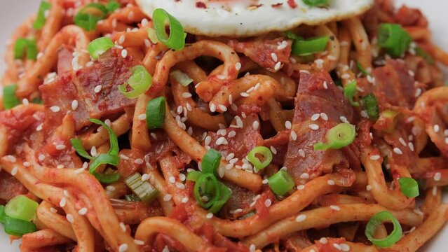 Kimchi Fried Udon Noodle with Fried Egg and bacon. Korean food. Rotating video