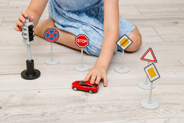 cute little girl playing at home on the floor with a road signs and traffic lights