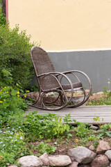 an empty old rocking chair stands in the courtyard of the house  