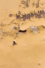 old cracked yellow wall and peeling paint with cracks (vertical frame) 