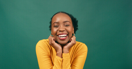 Beautiful Black woman cups hands under chin in cute pose, green studio