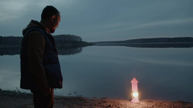People at dusk by the lake launch festive rockets. Romantic evening.