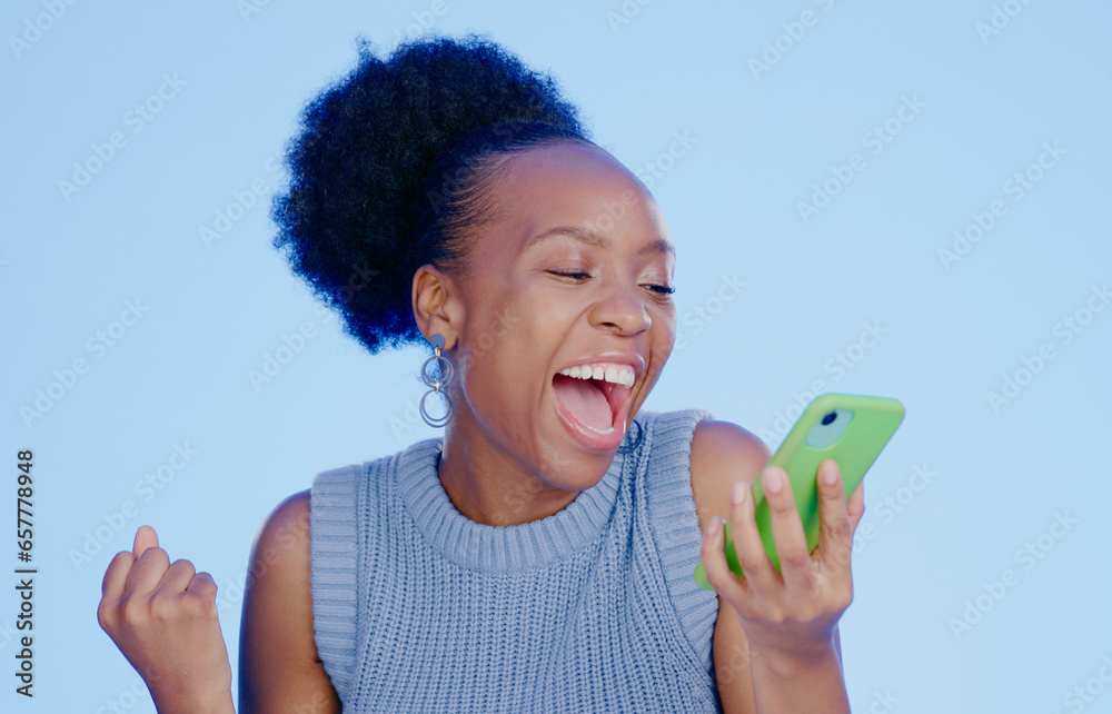 Poster Celebration. phone and young black woman in a studio with winning, achievement or success. Happy, smile and African female winner cheering with fist pump on cellphone isolated by blue background.