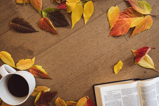 Christian bible, cup of coffee and autumn leaves on a light wood table with copy space
