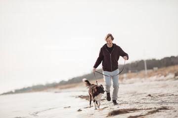 Middle aged man walking his Border Collie on the beach