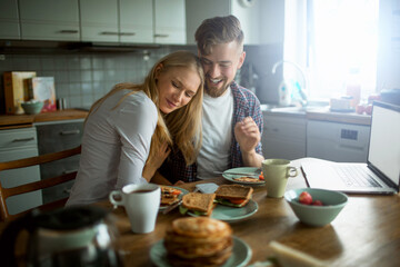 Young couple embracing each other while having breakfast in the kitchen