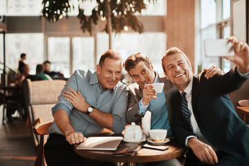Middle aged business people taking a selfie in a cafe decorated for christmas and the new year holidays