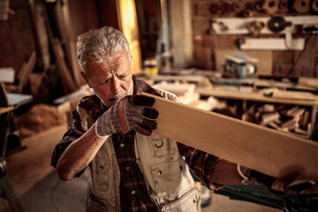 Senior male carpenter measuring wood in a carpentry shop