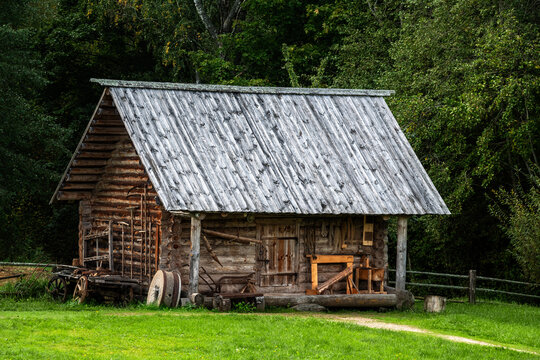 Old wooden barn log house with a wooden roof on a background of green forest.