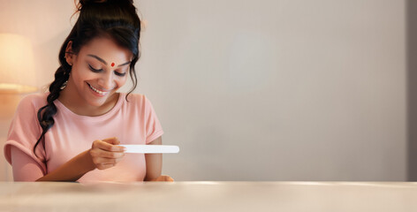 Moment of Happiness: Capturing the Radiant Expression of an Indian Woman Upon Discovering Her Pregnancy, Holding a Pregnancy Test in Her Hand
 - obrazy, fototapety, plakaty