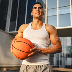 Portrait of strong athlete man hold basketball ball wear white a-shirt