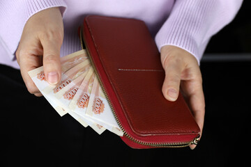 Woman takes out russian rubles from red wallet. Concept of wages in Russia, payments, assistance