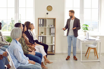 Young business man speaking on a work meeting in the office in front of a small group of diverse...
