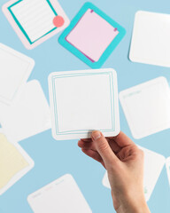 Woman's hand holding blank affirmation card with other cards in background on blue background 