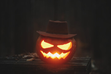 Spooky glowing Jack o lantern on autumn leaves in moody dark forest. Happy Halloween! Scary...