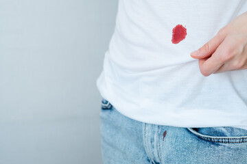 Drop stain of blood on a white t-shirt. daily life stain concept. Space for text - obrazy, fototapety, plakaty