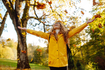 Hiking in the autumn forest. A smiling tourist in a bright coat walks through an autumn park in...