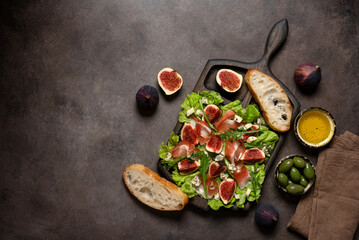 Fototapeta na wymiar Italian appetizer prosciutto ham , blue cheese, figs, olives and ciabatta on a wooden board, dark rustic background. Top view, flat lay.