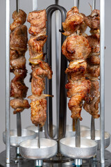 Cooking pork meat in an electric kebab maker on vertical skewers
