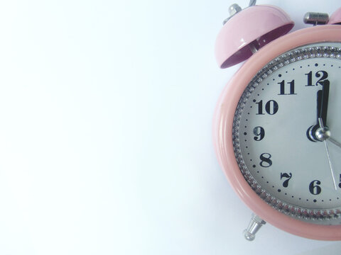 The old pink alarm clock showed one minute past twelve. isolated on white background close up view from above.