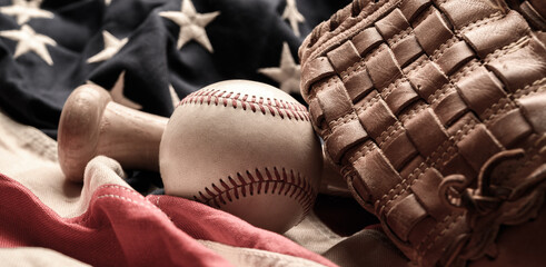 A baseball glove, bat and ball on American flag. The national pastime
