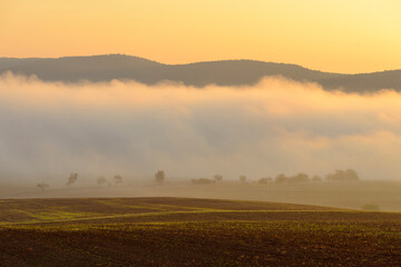 Countryside with morning mist over fields illuminated by the sun at Grossheubach in Bavaria, Germany