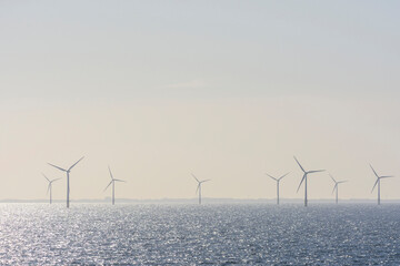 Offshore wind turbine farm with sun shining on the North Sea on a hazy morning, United Kingdom