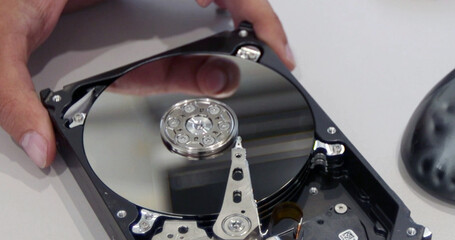 Close-up of an open hard disk drive in the hands of a technician