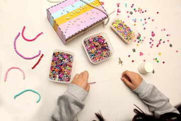 Teenage woman's hands make friendship bracelets to sell, give and exchange with her friends at...